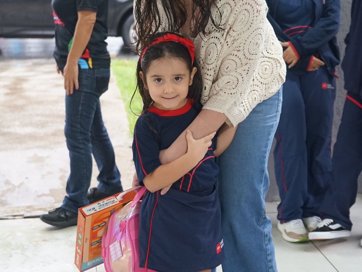 Mãe abraçando filha em uniforme da Educação Infantil no Colégio Alceu Cotta.